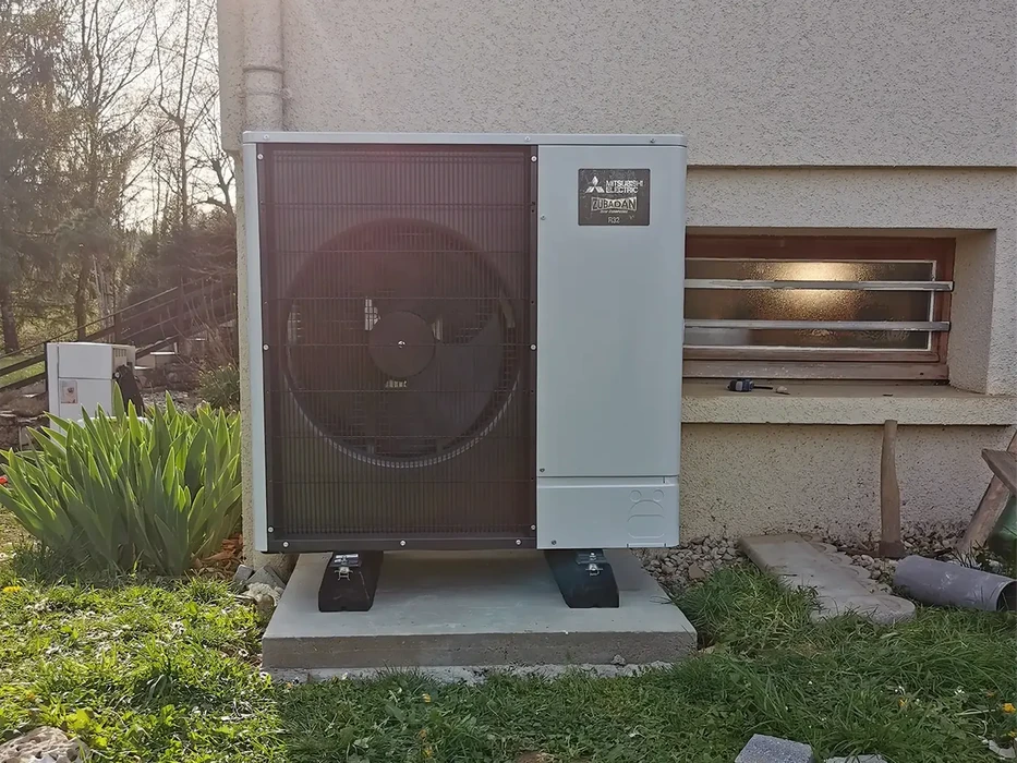 Extérieur résidentiel avec pompe à chaleur air-eau Mitsubishi Electric Zubadan installée sur dalle béton
