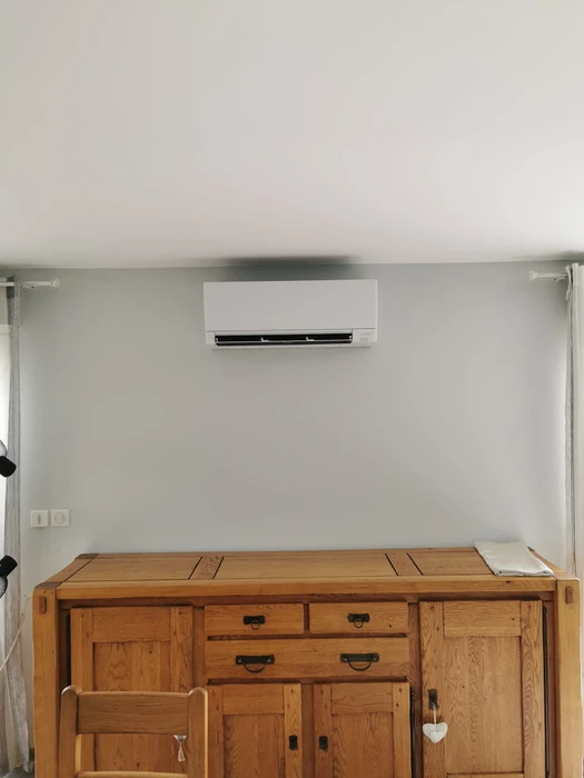 Extérieur résidentiel avec deux unités de climatisation installées sur dalle béton contre mur en bois