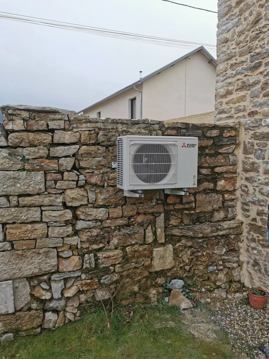 Extérieur d'un bâtiment résidentiel avec unité de climatisation installée contre un mur texturé beige