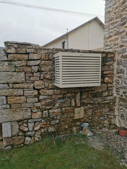 Extérieur d'une maison avec unité extérieure de climatisation Mitsubishi Electric montée au mur